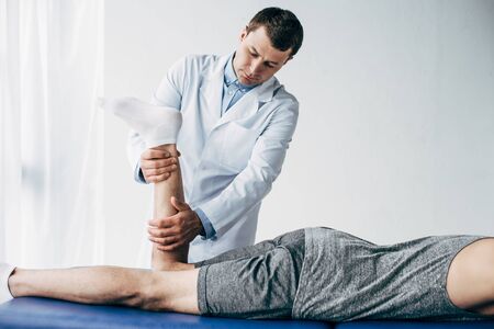 Physiotherapist stretching leg of patient in hospitalの写真素材