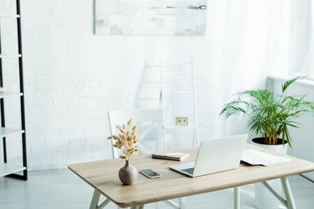 Laptop and smartphone with blank screen on wooden table in modern officeの写真素材