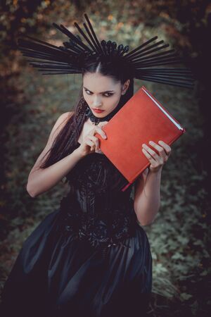 High angle view of woman in costume holding red book in hands, looking awayの写真素材