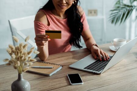 Cropped view of Asian woman holding credit card near laptop and smartphoneの写真素材