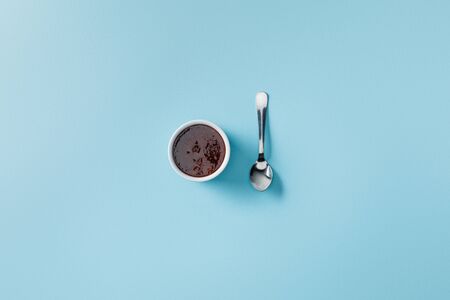 Top view of teaspoon near jam in bowl on blue backgroundの写真素材
