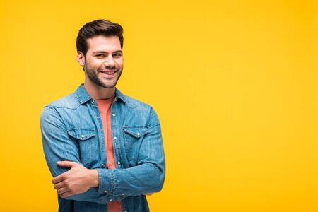 Smiling handsome man with crossed arms isolated on yellow background with copy spaceの写真素材