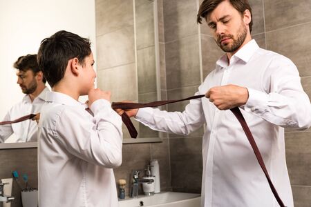 Father and son dressing in formal wear in bathroomの写真素材