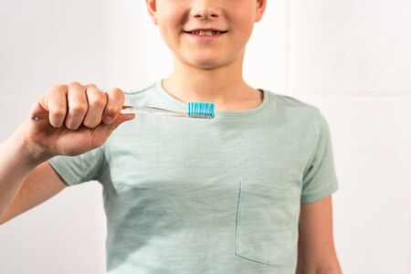 Cropped view of smiling boy holding toothbrush in bathroom