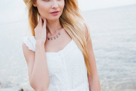 Cropped view of blonde young woman touching neckの写真素材