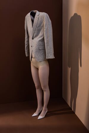 Stylish woman holding blazer over head, standing on brown backgroundの写真素材