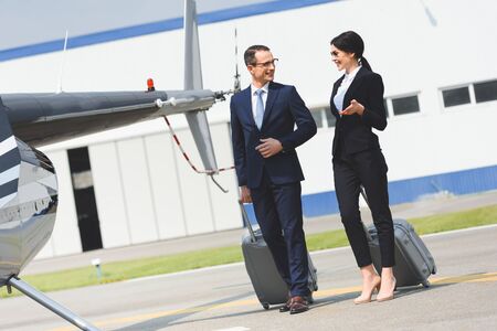 Business partners in formal wear with luggage near helicopterの写真素材