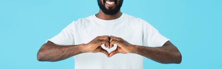 Cropped view of cheerful African American man showing heart sign isolated on blue backgroundの写真素材