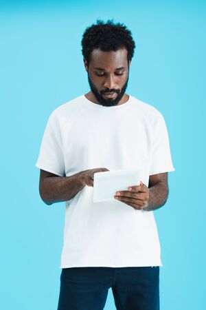 Handsome African American man using digital tablet isolated on blue background