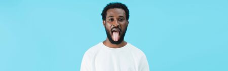 African American man sticking tongue out isolated on blue background