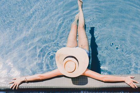 Overhead view of young woman in straw hat relaxing in swimming poolの写真素材