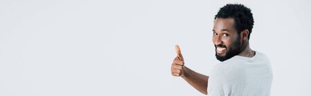 Cheerful African American man in grey t-shirt showing thumb up isolated on grey backgroundの写真素材