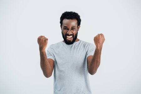 Excited African American man in grey t-shirt posing isolated on grey backgroundの写真素材