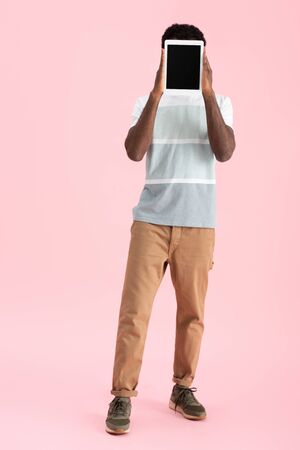 African American man showing digital tablet with blank screen isolated on pink backgroundの写真素材