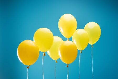 Bright colorful yellow balloons on blue backgroundの写真素材