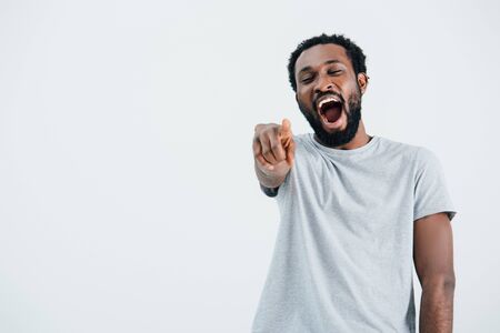 African American man laughing and pointing isolated on grey backgroundの写真素材