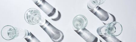 Top view of transparent glasses with pure water on white background, panoramic shot