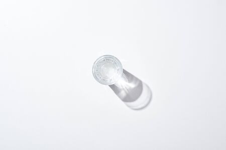 Top view of transparent glass with water on white surface with shadowの写真素材
