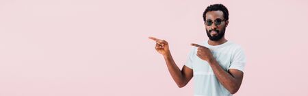 Smiling African American of man in sunglasses pointing aside, isolated on pink backgroundの写真素材