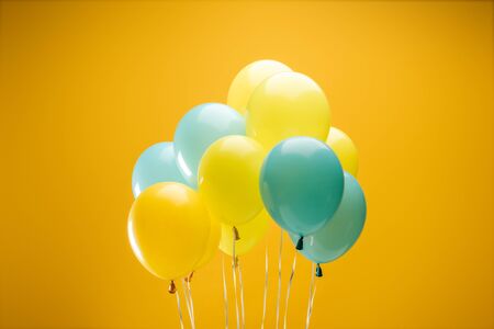 Festive decorative blue and yellow balloons on yellow backgroundの写真素材