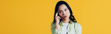 Attractive brunette Asian girl having headache isolated on yellow background