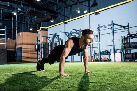 Handsome athletic man doing plank exercise on grass