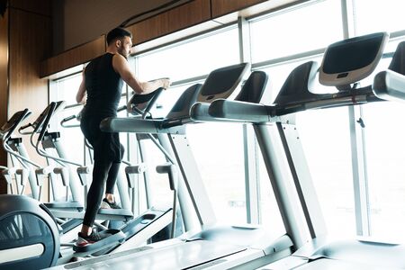 Low angle view of athletic and handsome man working on out on exercise bike in gym