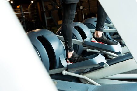 Cropped view of athletic man working out on exercise bike in gym