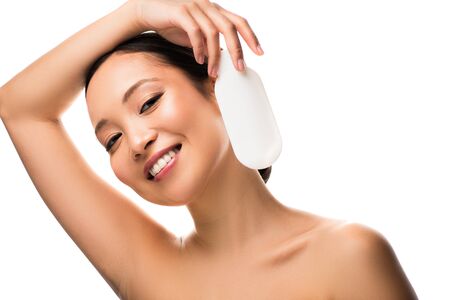 Cheerful Asian girl with bottle of lotion, isolated on white background