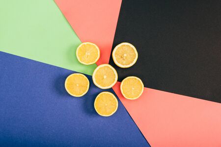 Top view of bright yellow cut lemons on multicolored black blue coral green backgroundの写真素材