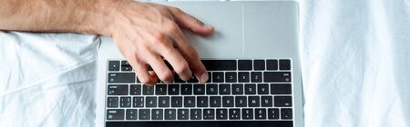 Panoramic shot of man typing on laptop keyboard, illustrative editorial