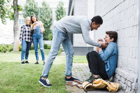 African american boy in hoodie and jeans bulling boy and teenager shooting itの写真素材