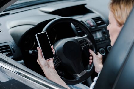 Cropped view of woman holding smartphone with blank screen in carの写真素材