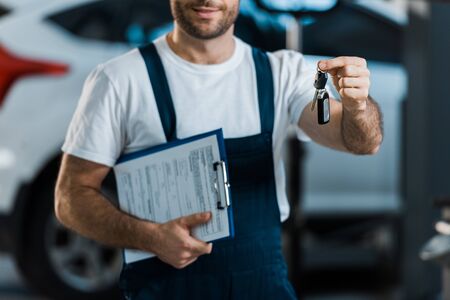Cropped view of car mechanic holding clipboard and keyの写真素材