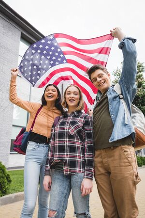 Happy teenagers smiling, holding american flag and looking at cameraの写真素材