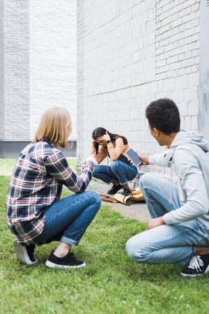 African american boy and blonde teenager shooting scared brunette teenagerの写真素材