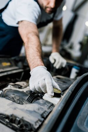 Cropped view of car mechanic touching cap in automobileの写真素材