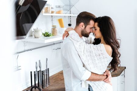 Lovely gently couple embracing with closed eyes at kitchenの写真素材