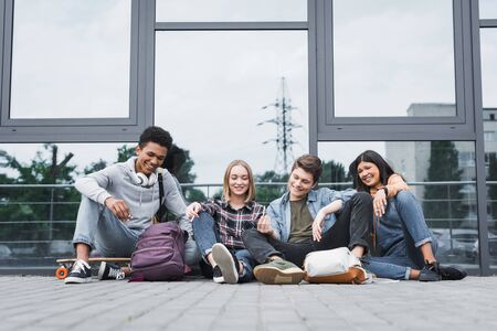 Happy and positive friends smiling, sitting and smoking cigarettes
