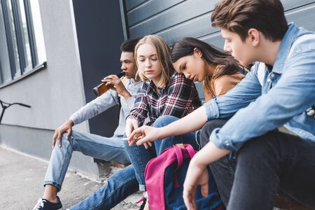 Teenagers sitting, drinking beer from glass bottle and smoking cigaretteの写真素材