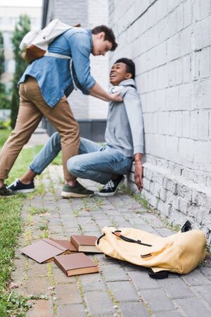 Aggressive boy in shirt bulling frightened African American boy in hoodie