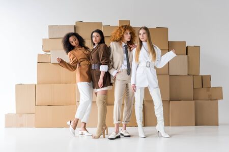 pretty young multicultural women posing near boxes on whiteの写真素材