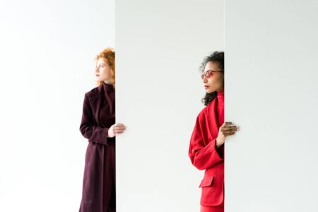 attractive redhead girl and african american woman standing on whiteの写真素材