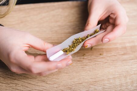 cropped view of girl rolling joint with medical cannabisの写真素材