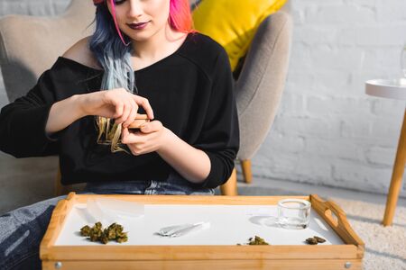 girl closing herb grinder with medical cannabis sitting on floor in living roomの写真素材