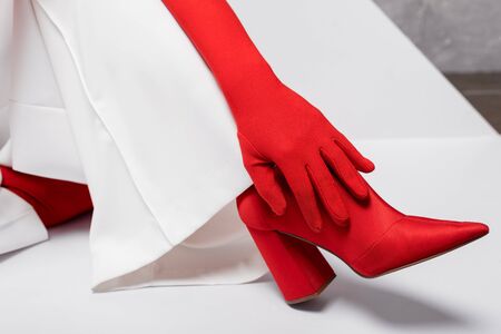 cropped view of stylish young woman in red glove and shoe on whiteの写真素材