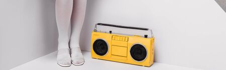 panoramic shot of woman posing near retro yellow boombox on whiteの写真素材