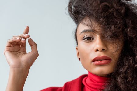 close up of attractive brunette african american woman looking at camera and gesturing isolated on...