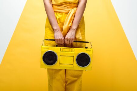 cropped view of woman posing with retro boombox on white and yellowの写真素材