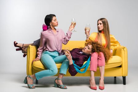 african american girl near redhead and blonde women with champagne glasses on whiteの写真素材